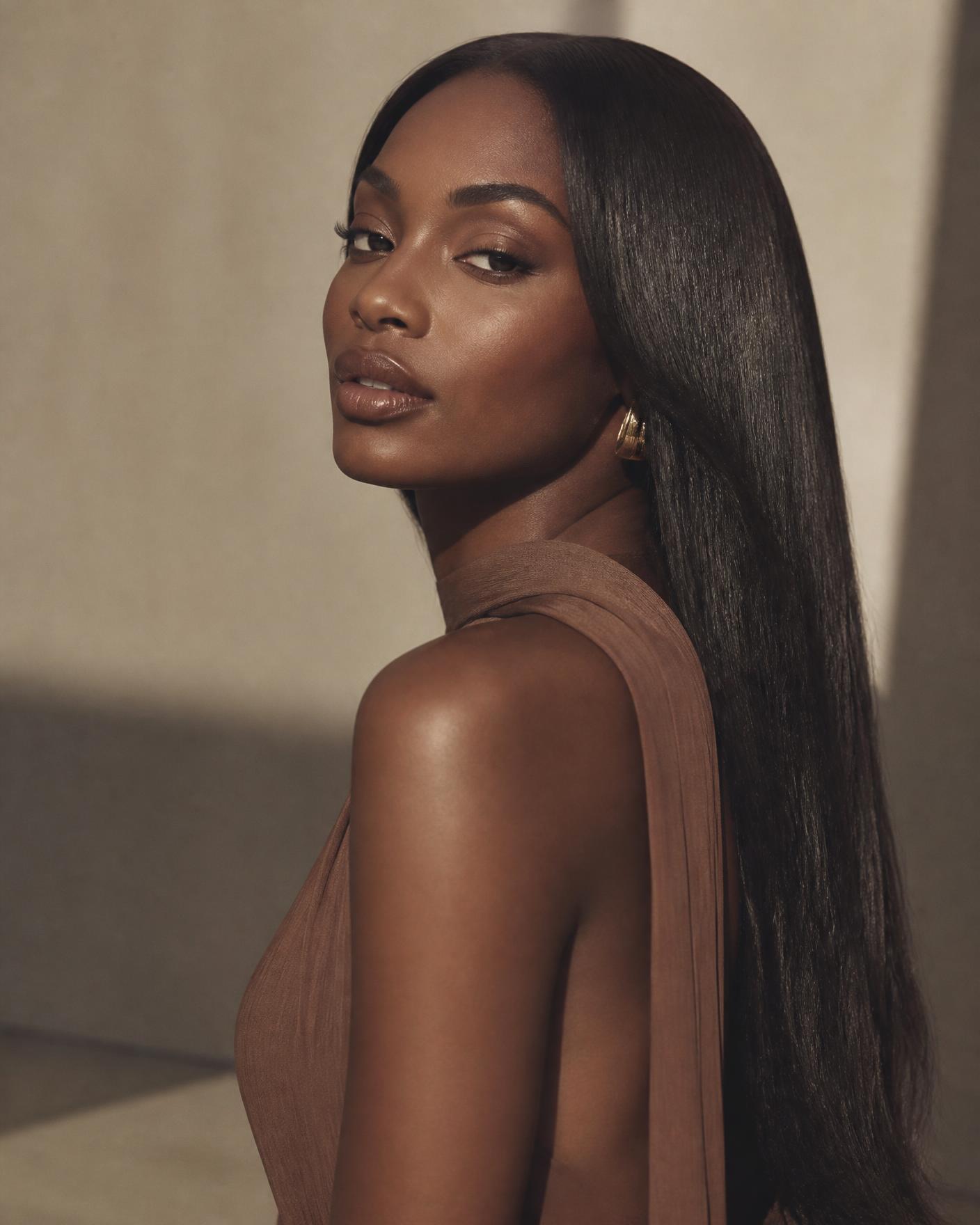 Model wearing a sleek, glossy Kady Hairs straight wig in warm studio light